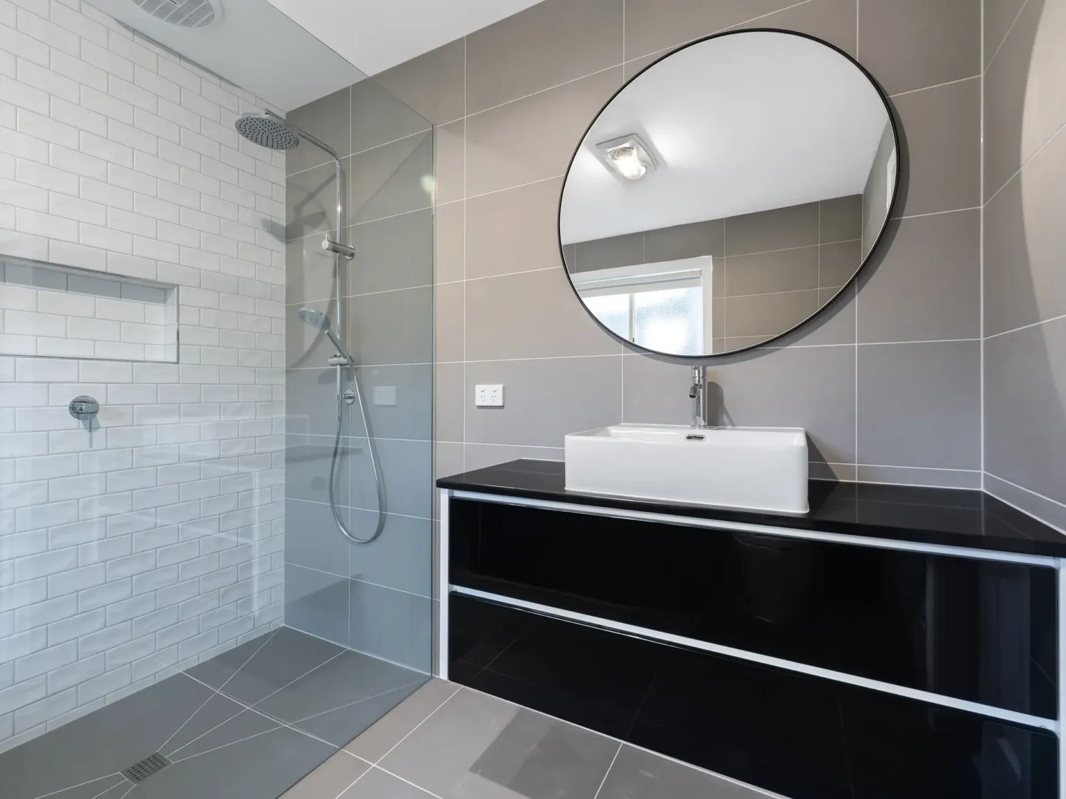 Modern vanity with round mirror and view of frameless shower