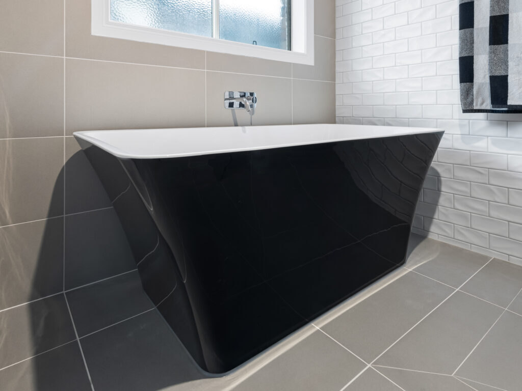 Freestanding bath with sleek black exterior and chrome tapware