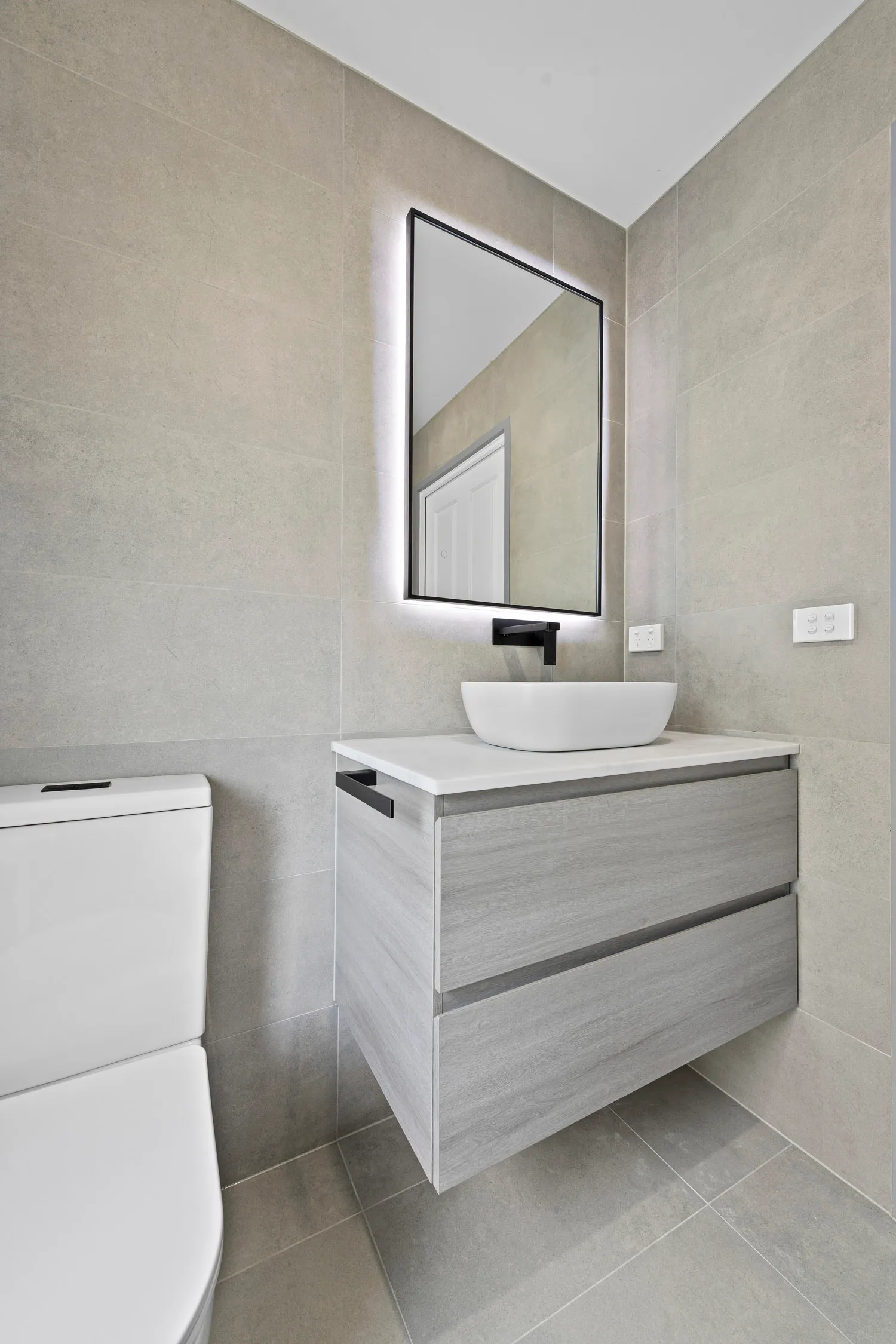 Backlit mirror and vessel basin with matte black tapware in renovated Chirnside Park bathroom