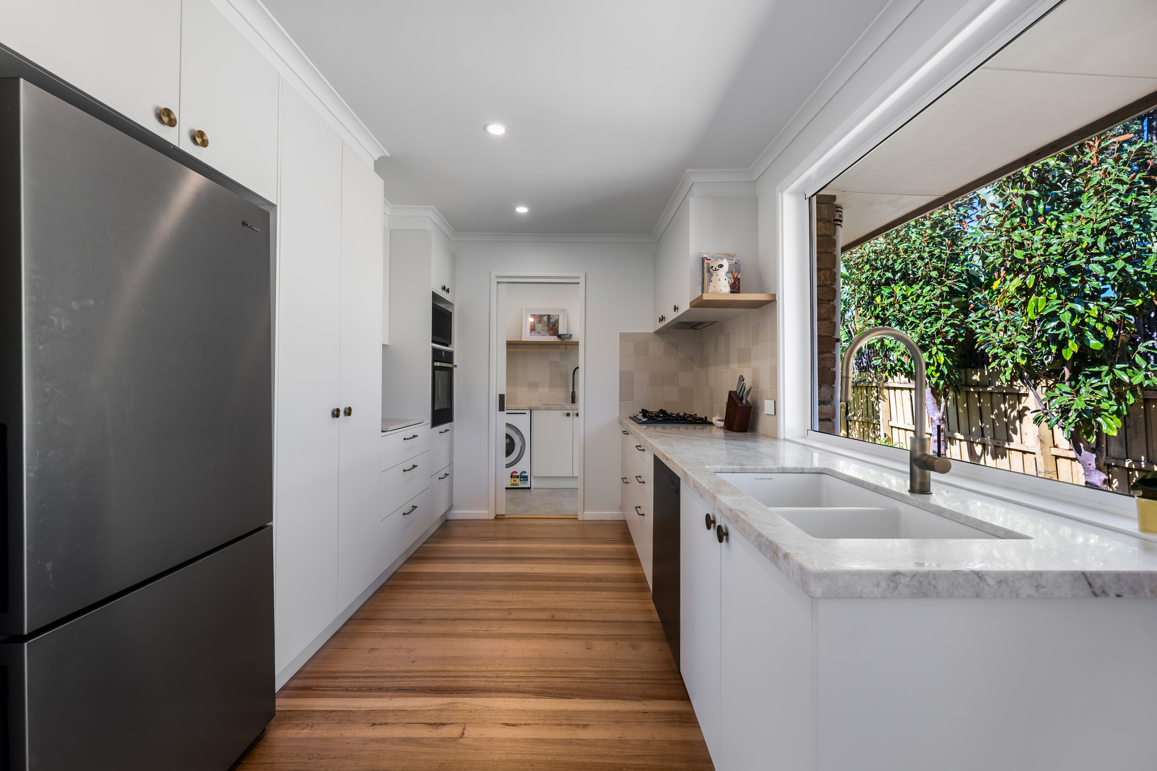 Modern Brighton kitchen with white cabinetry, stainless steel fridge, and timber flooring.