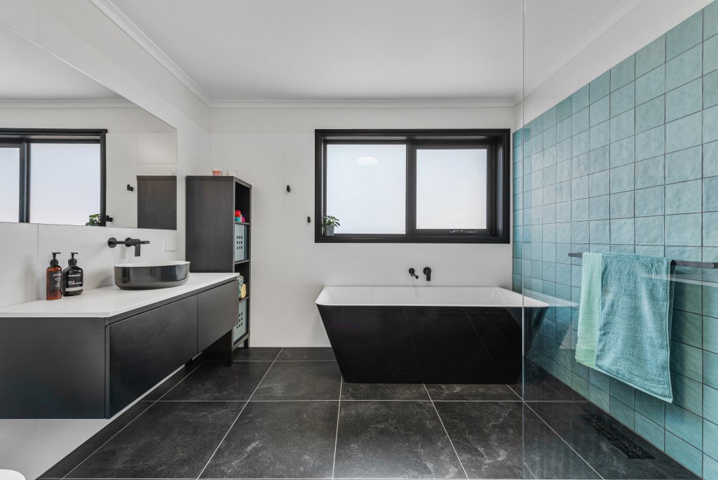 Freestanding black and white bathtub with matte aqua feature wall tiles in Croydon bathroom renovation