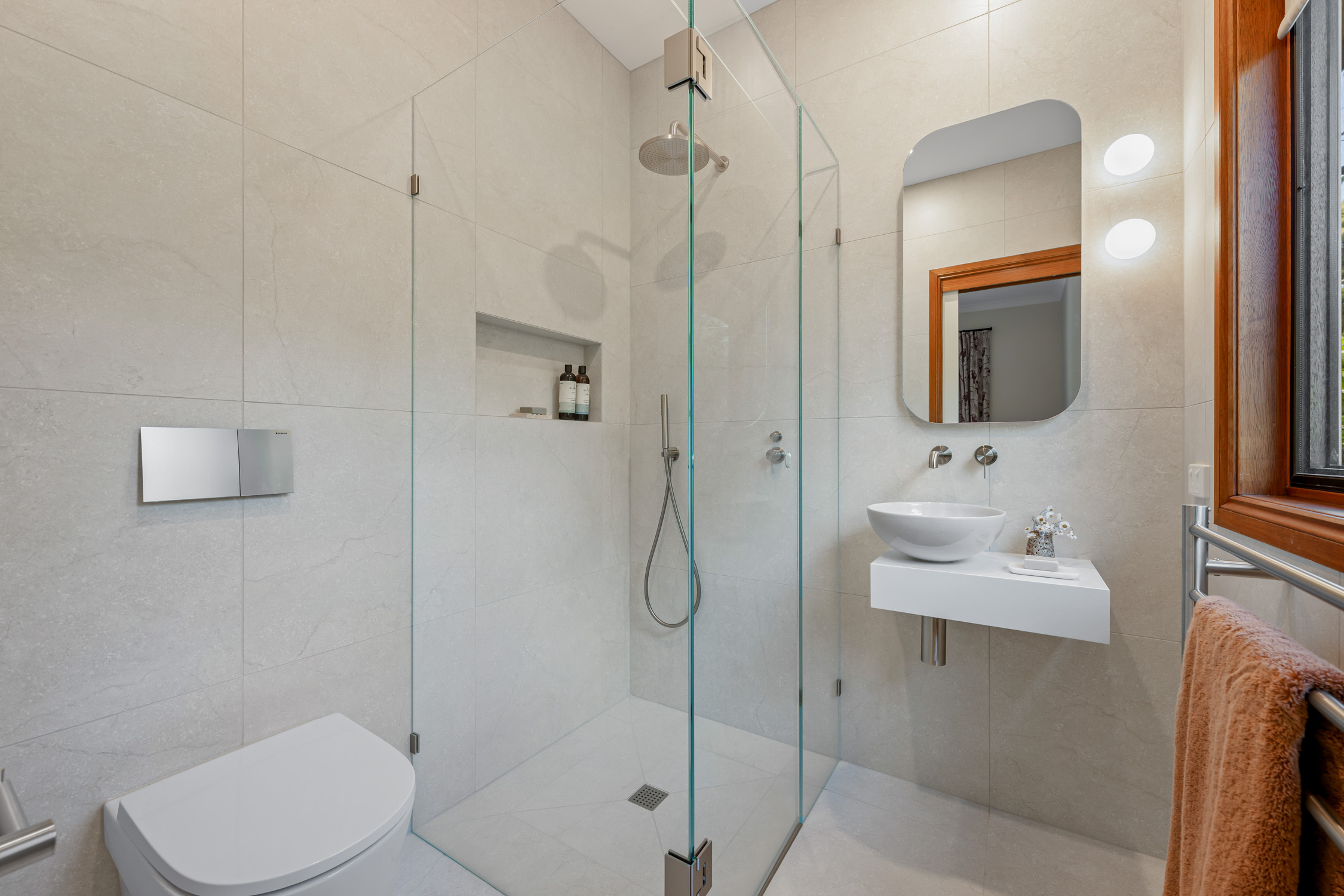 Frameless shower screen with overhead rain shower and tiled niche