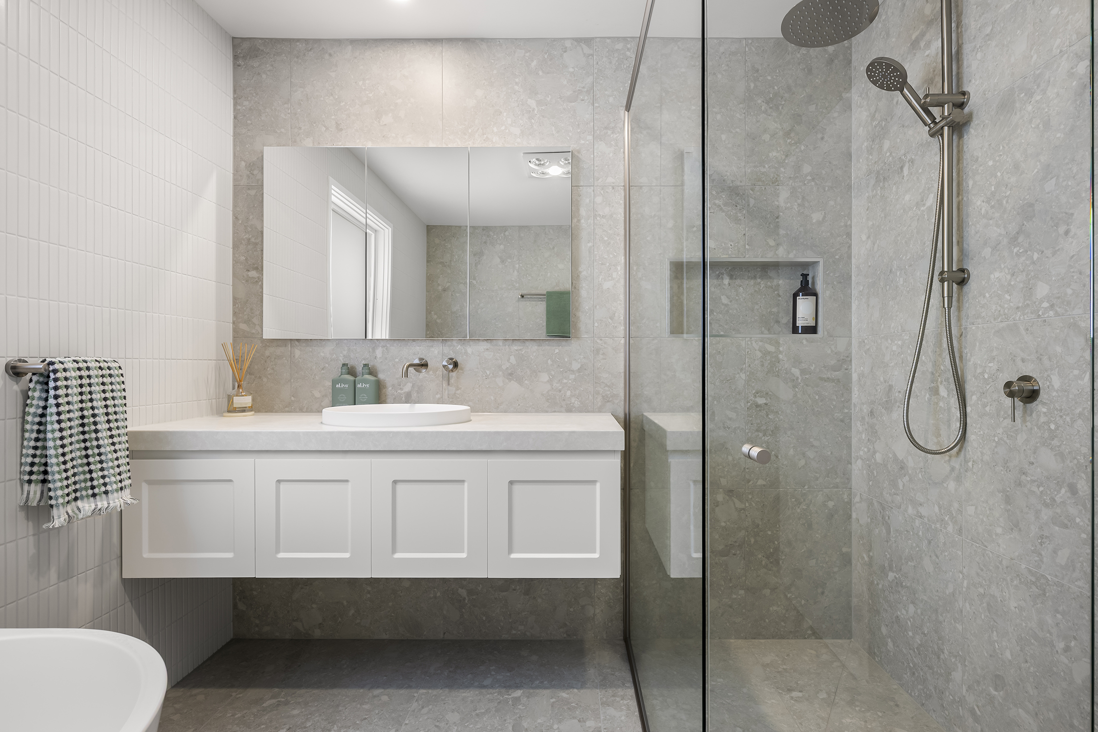 Close-up view of a minimalist bathroom vanity with a round white basin, custom tapware, and natural decor accents.