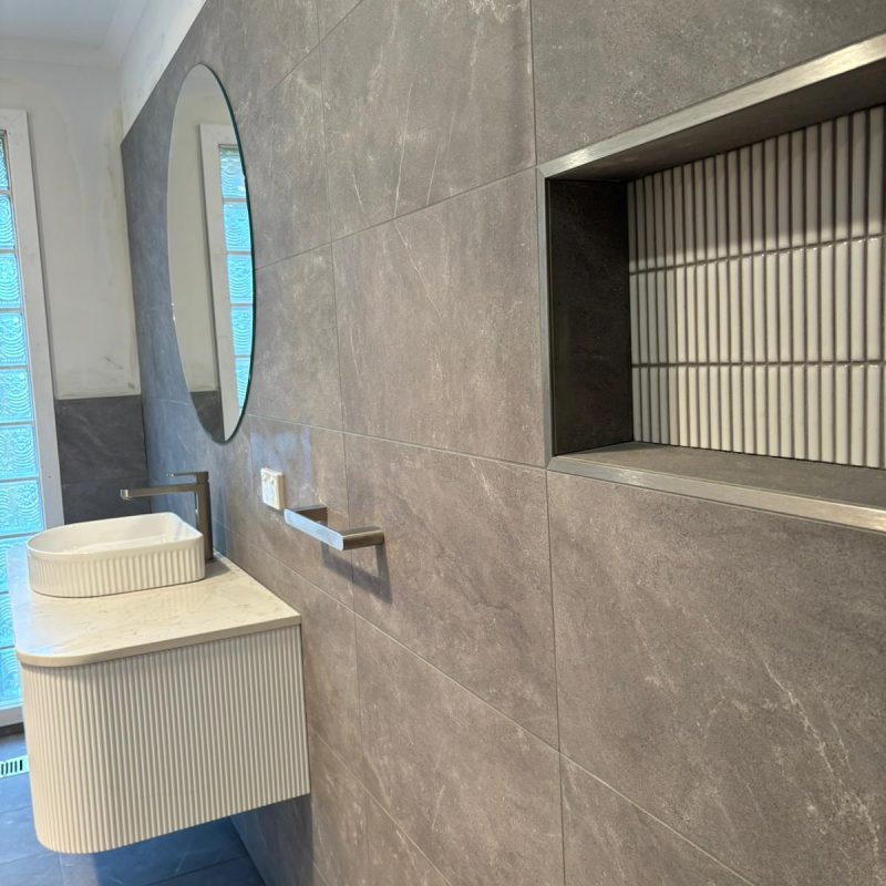 Custom ribbed vanity and round mirror with glass brick light wall in luxury bathroom