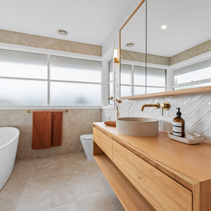 Timber vanity with stone vessel basin and brushed brass tapware in Doncaster ensuite renovation.