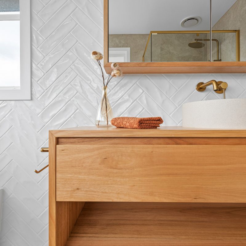 Brushed brass rain shower with recessed niche and large-format natural stone-look tiles.