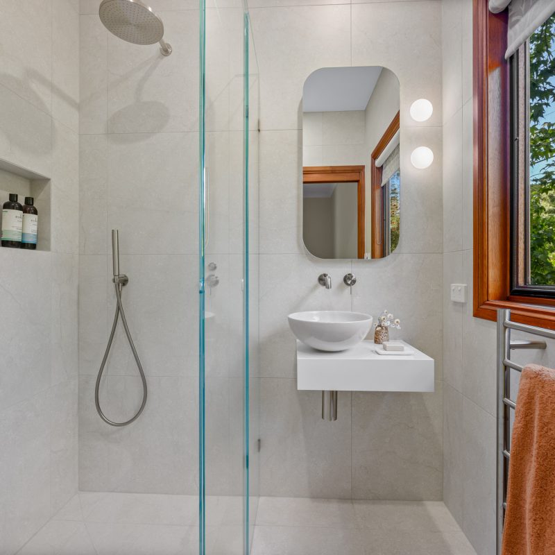Close-up of wall-mounted basin mixer over ceramic countertop basin