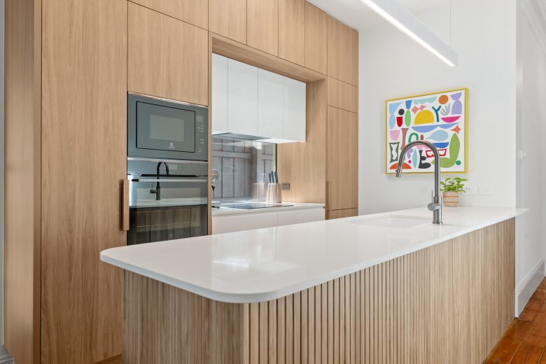 Modern kitchen with white island bench and timber finishes