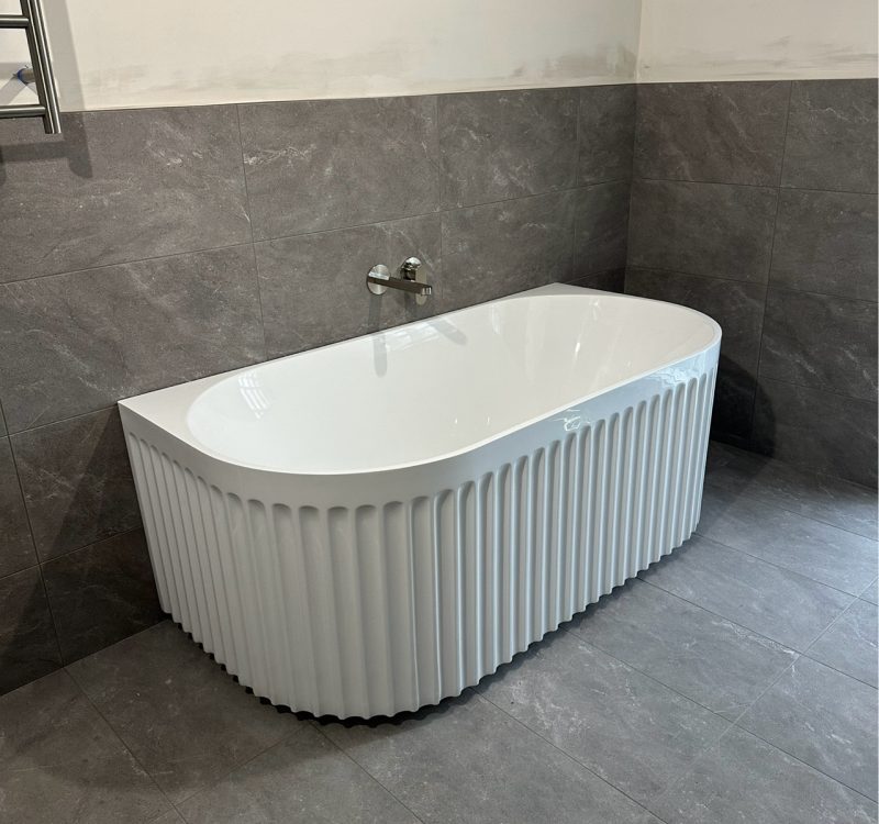 Matte grey tiled walk-in shower with twin rail showerhead and vertical tile niche