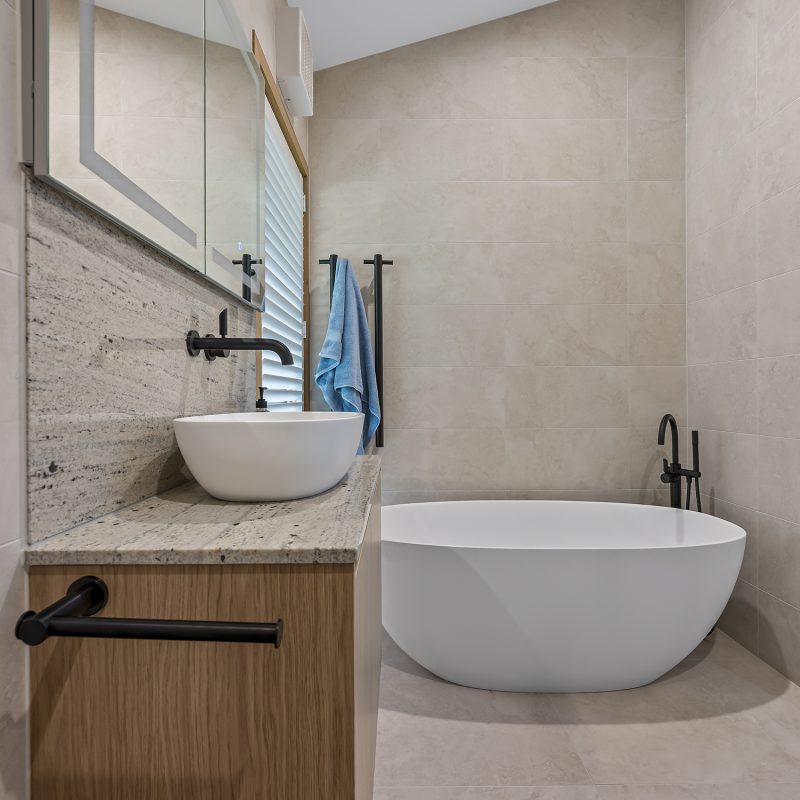 Modern bathroom featuring freestanding bathtub, timber vanity with stone benchtop and frameless shower.